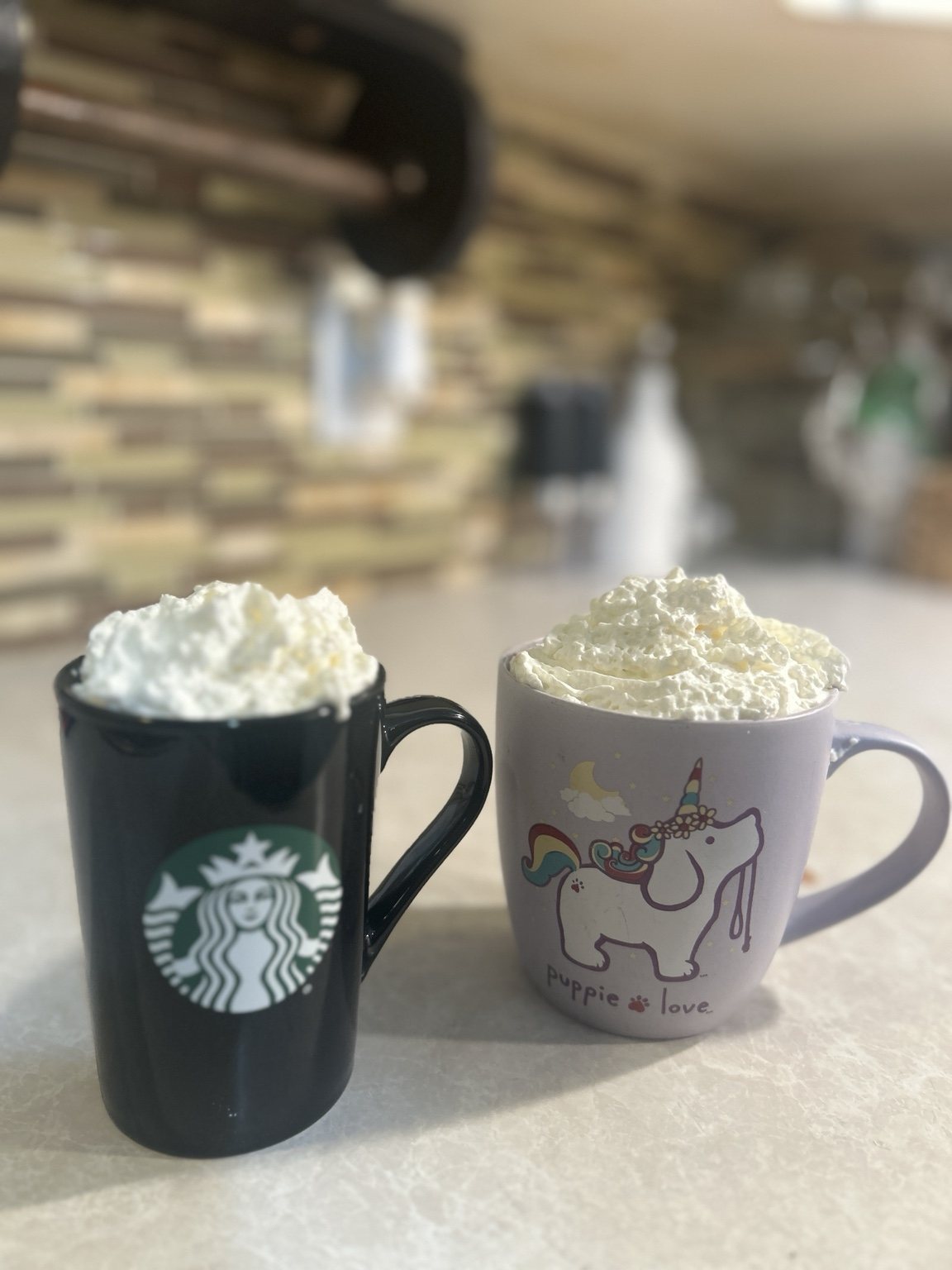 Two mugs with whipped drinks in a home kitchen