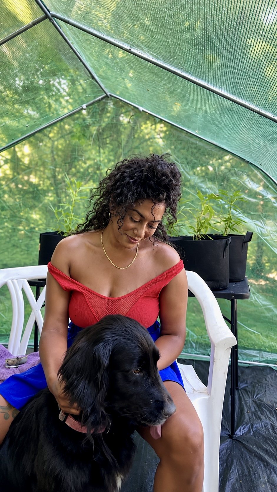 Brittney J in greenhouse with dog and plants